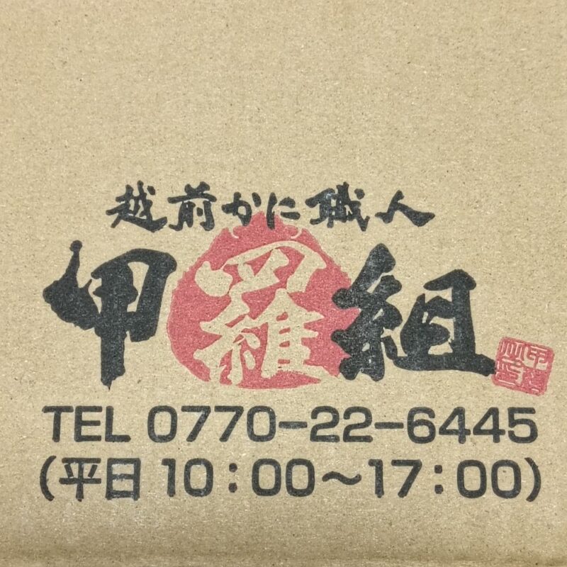 越前かに職人甲羅組 生ズワイガニ 肩肉 1kg×3個入の箱にあるロゴと電話番号と営業時間。