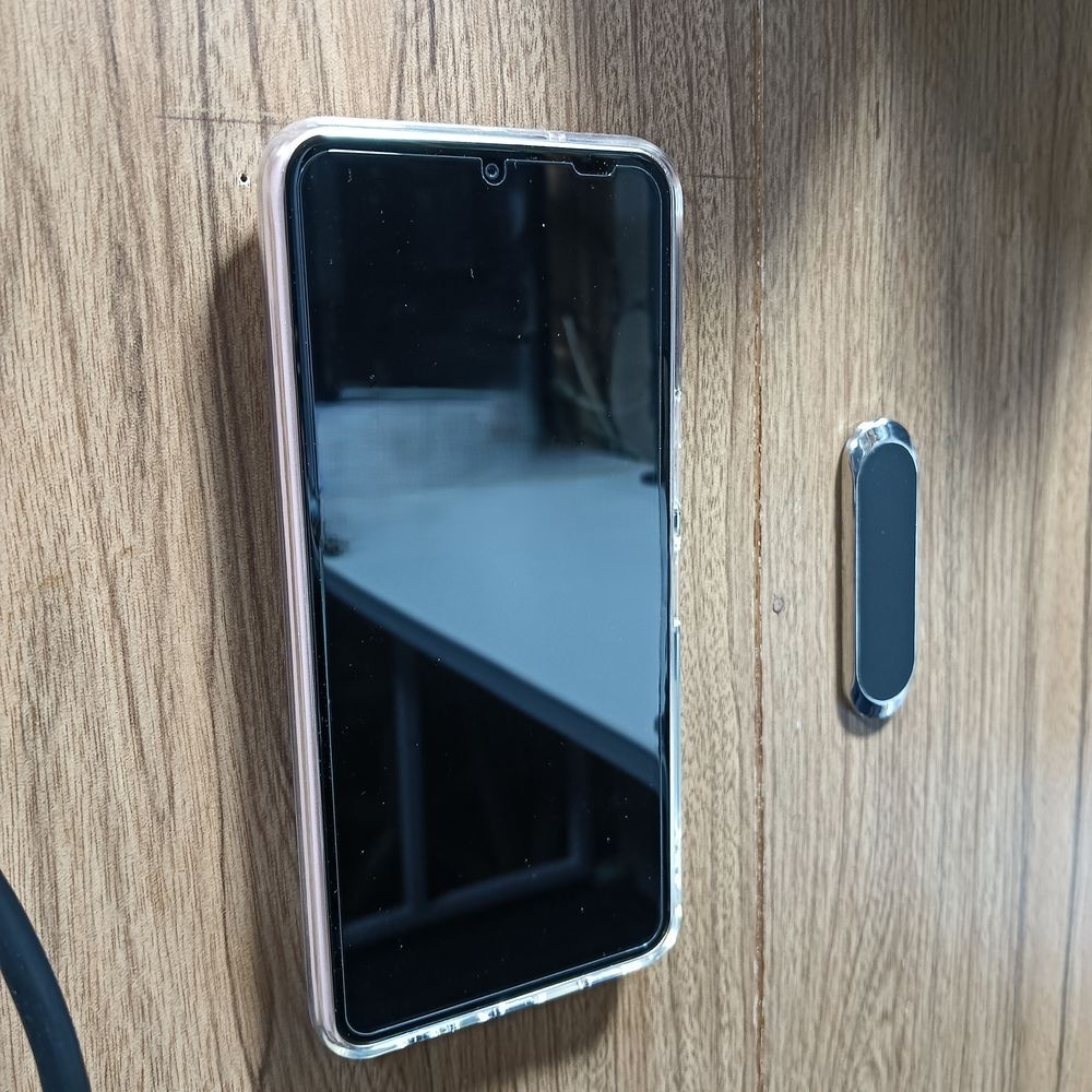 壁に貼った強力ネオジム磁石搭載のスマホホルダーに磁石でスマホが貼りついている。