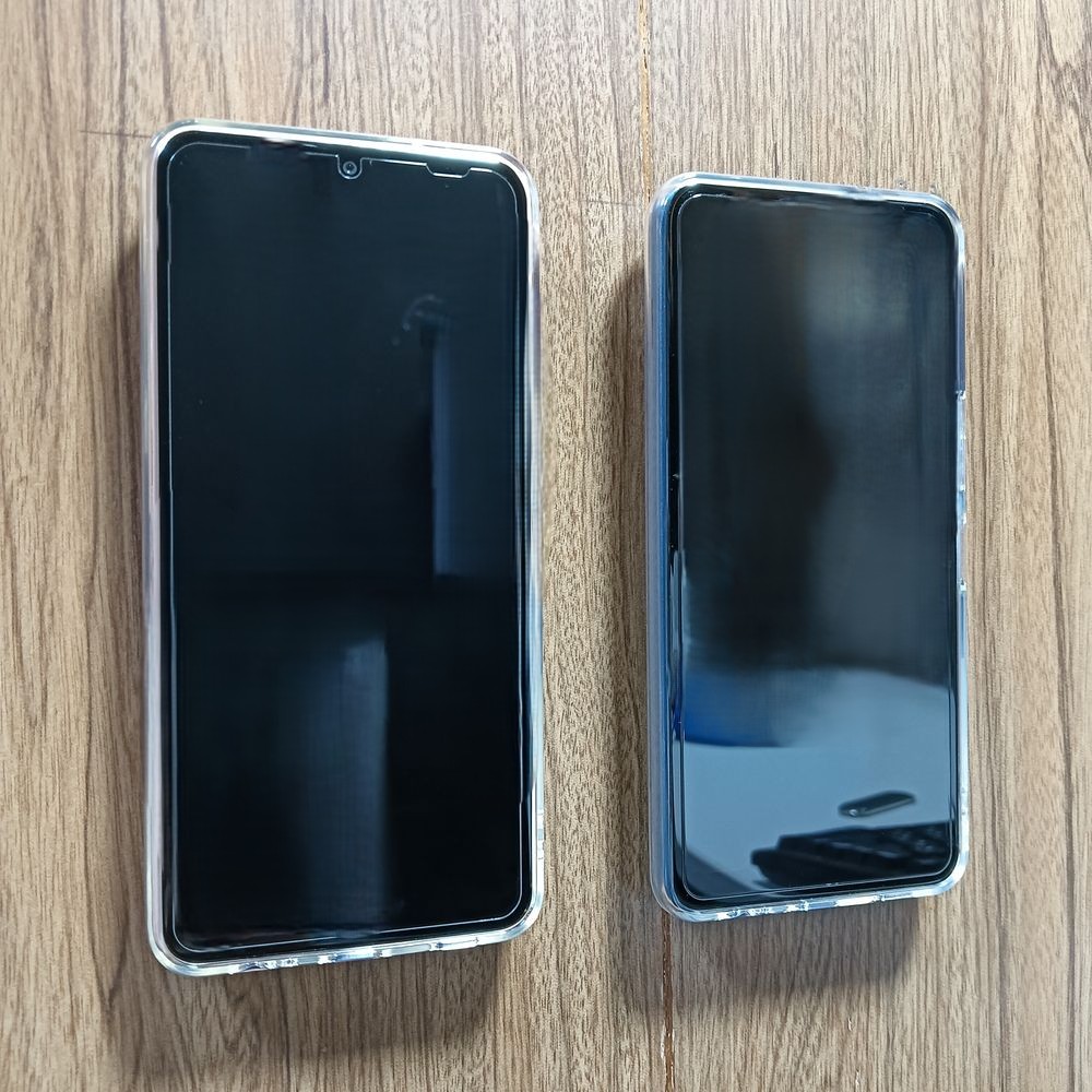 壁に貼った強力ネオジム磁石搭載のスマホホルダーに磁石でくついたスマホ2台。